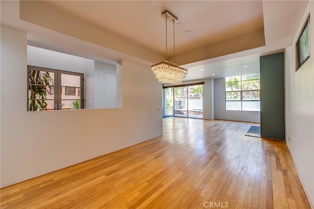 empty room with a chandelier and light wood-type flooring