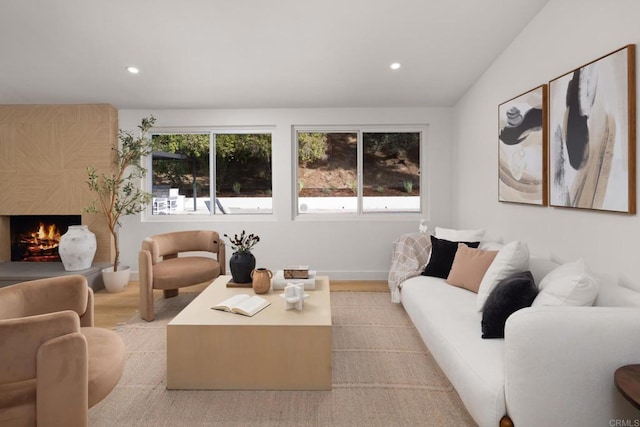 living room with plenty of natural light, light hardwood / wood-style floors, a large fireplace, and vaulted ceiling