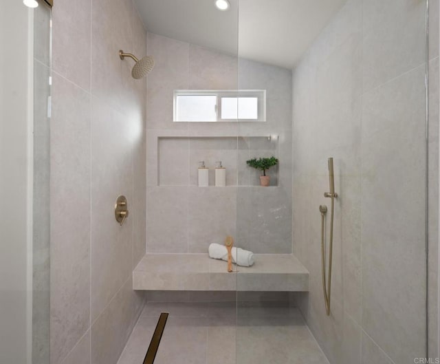 bathroom featuring lofted ceiling and a tile shower