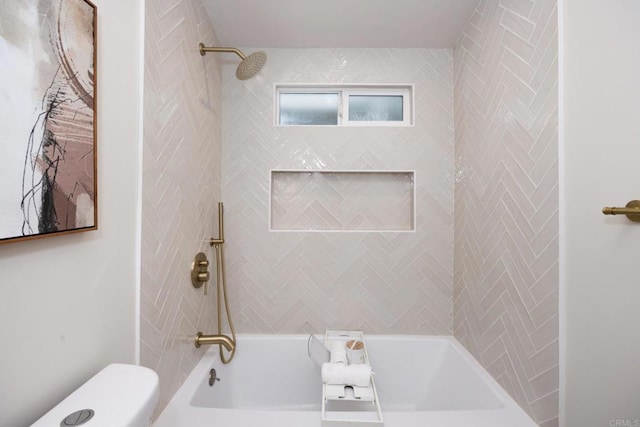 bathroom featuring tiled shower / bath combo and toilet