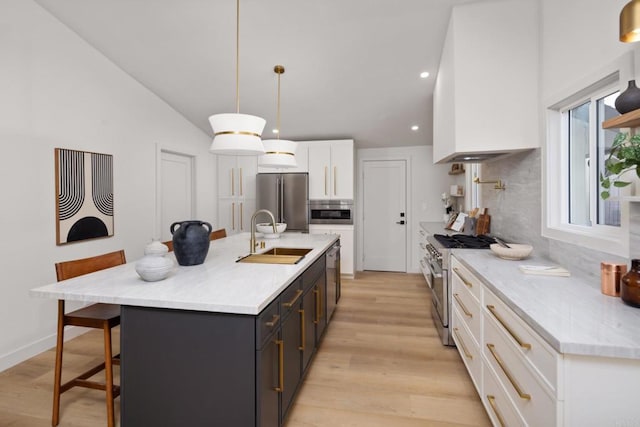 kitchen featuring appliances with stainless steel finishes, pendant lighting, an island with sink, sink, and white cabinets