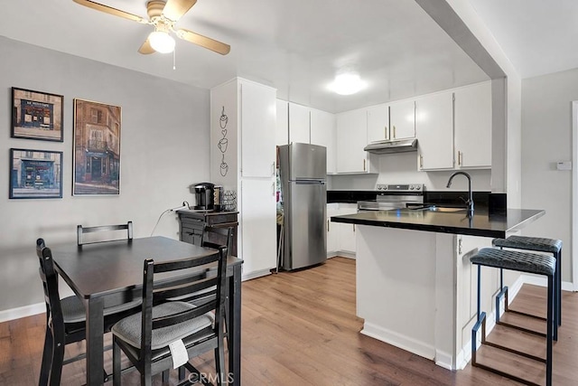 kitchen with sink, white cabinetry, light wood-type flooring, kitchen peninsula, and stainless steel appliances