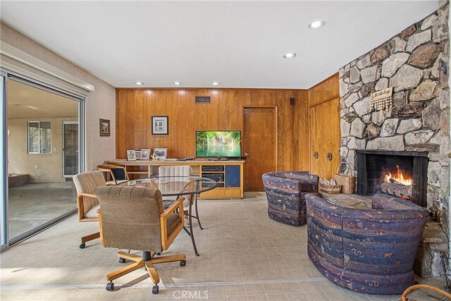 dining room with a fireplace and wood walls