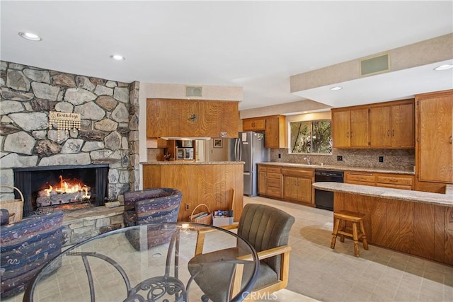 kitchen featuring a stone fireplace, sink, tasteful backsplash, stainless steel fridge, and dishwasher