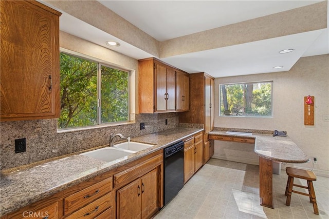 kitchen featuring tasteful backsplash, sink, light stone countertops, and dishwasher