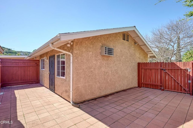 view of property exterior with a patio area, a gate, and stucco siding