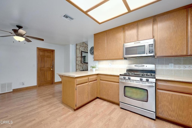 kitchen with a peninsula, visible vents, stainless steel appliances, and light countertops