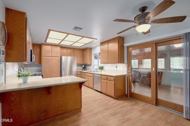 kitchen with stainless steel appliances, a peninsula, a sink, visible vents, and light countertops