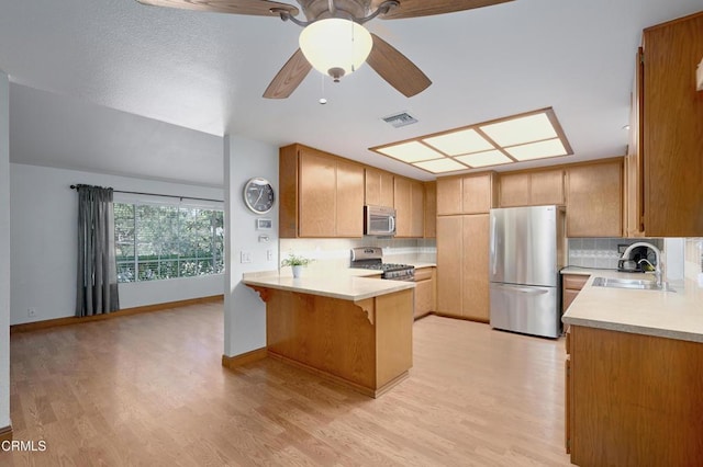 kitchen with stainless steel appliances, light countertops, visible vents, a sink, and a peninsula