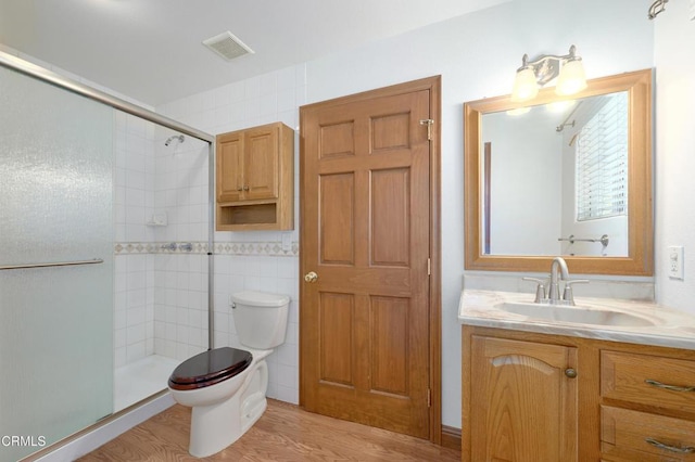 full bath featuring visible vents, tiled shower, toilet, wood finished floors, and vanity