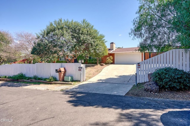 view of front of home featuring a fenced front yard, a chimney, an attached garage, a gate, and driveway