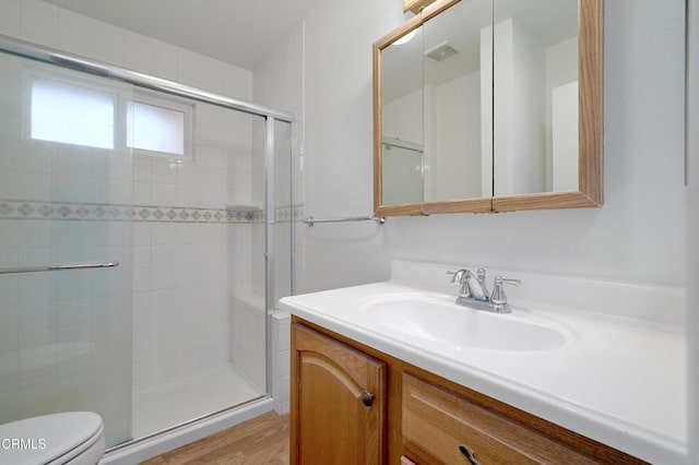 bathroom featuring visible vents, a shower stall, toilet, and vanity