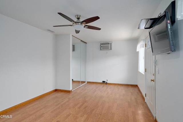 spare room with visible vents, light wood-style floors, a ceiling fan, a wall mounted air conditioner, and baseboards