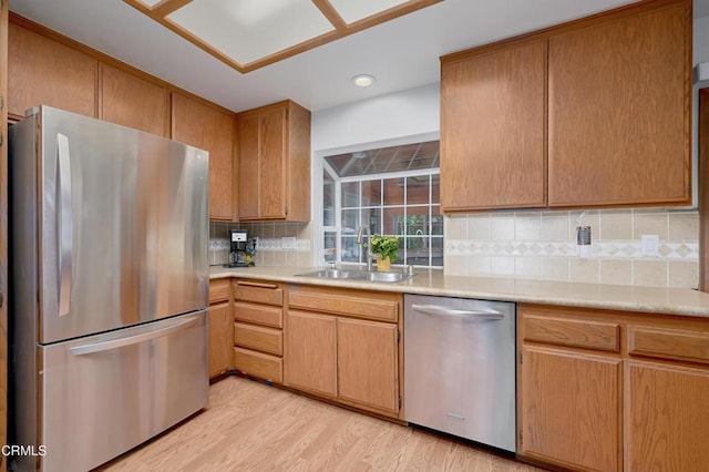 kitchen with stainless steel appliances, light countertops, a sink, and light wood finished floors