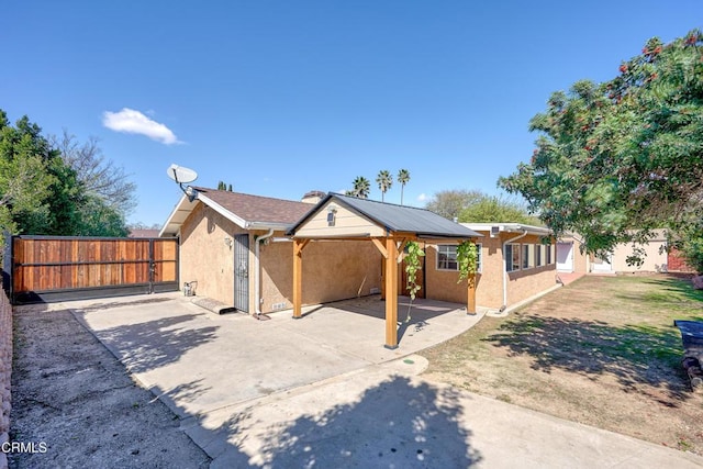 view of front of home with a patio, fence, a carport, and stucco siding