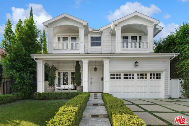 view of front of house with a garage, a balcony, and a front yard