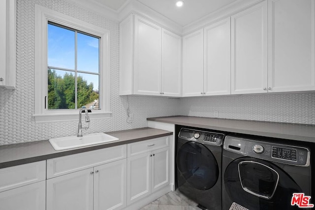 laundry area with cabinets, washing machine and dryer, and sink