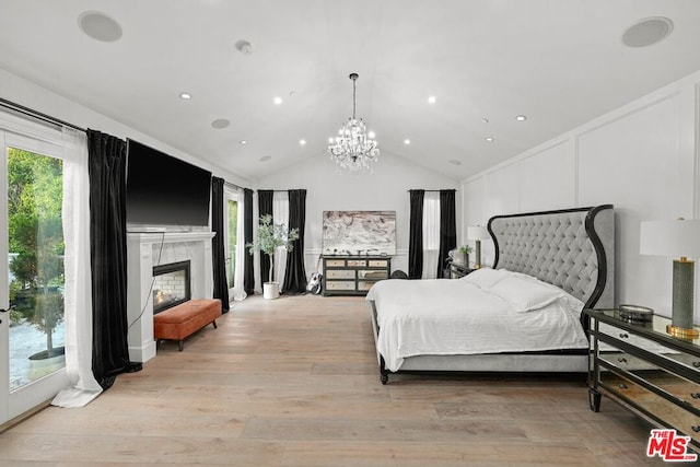 bedroom featuring multiple windows, vaulted ceiling, access to exterior, and light wood-type flooring