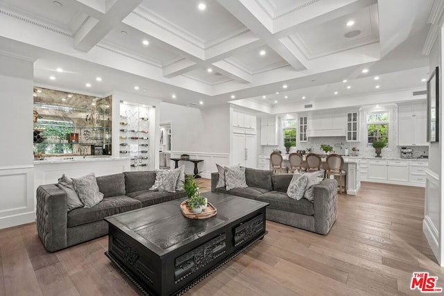 living room with beamed ceiling, ornamental molding, coffered ceiling, and light hardwood / wood-style flooring