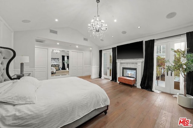 bedroom featuring hardwood / wood-style flooring, an inviting chandelier, a high end fireplace, access to outside, and french doors