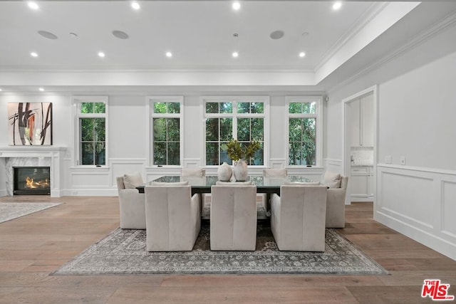 dining area featuring crown molding, a high end fireplace, and light hardwood / wood-style floors