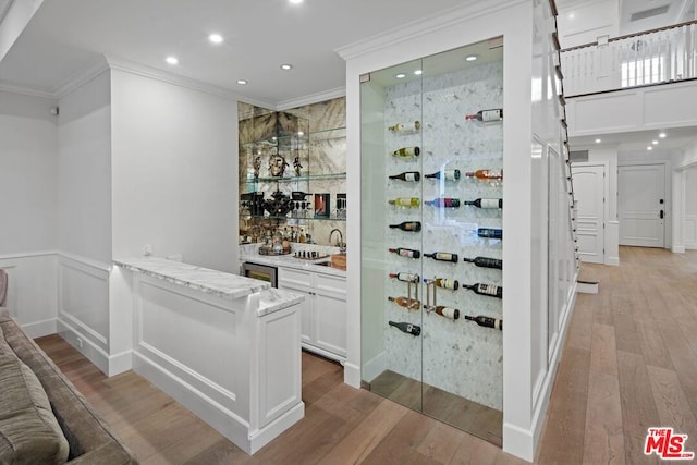 wine cellar featuring ornamental molding, indoor wet bar, and light wood-type flooring