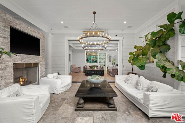 living room with ornamental molding, a fireplace, and a notable chandelier