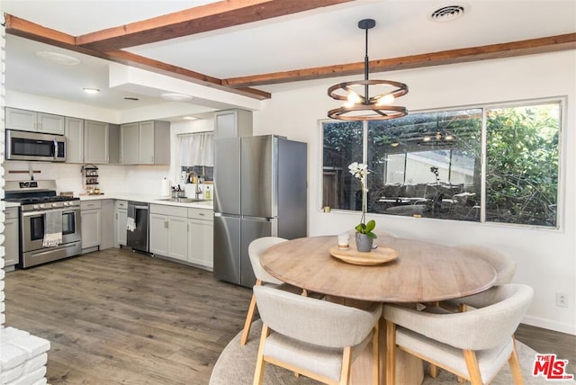 kitchen with sink, hanging light fixtures, beam ceiling, stainless steel appliances, and dark hardwood / wood-style flooring