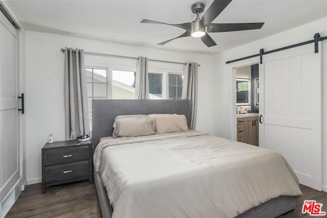 bedroom featuring multiple windows, dark hardwood / wood-style floors, and a barn door