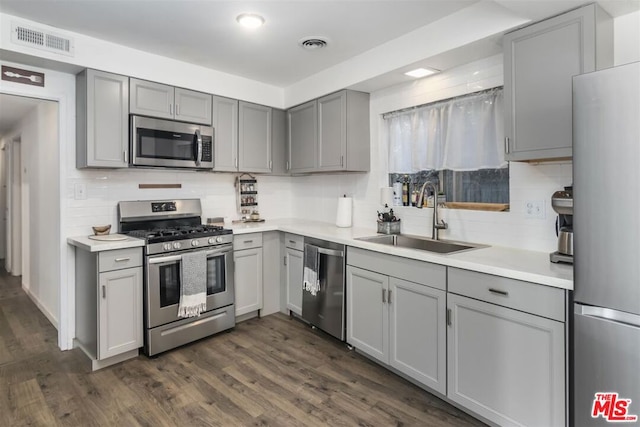 kitchen with gray cabinetry, sink, stainless steel appliances, and dark hardwood / wood-style floors