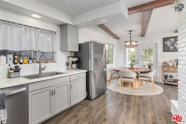 kitchen with hardwood / wood-style floors, sink, gray cabinetry, hanging light fixtures, and stainless steel appliances