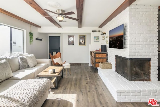 living room featuring hardwood / wood-style flooring, ceiling fan, a brick fireplace, and beamed ceiling