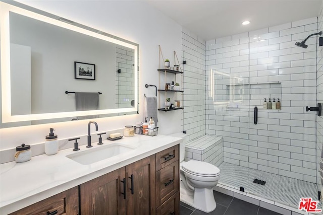 bathroom featuring vanity, tile patterned flooring, toilet, and walk in shower