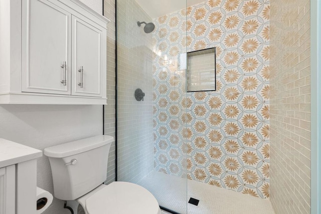 bathroom featuring vanity, toilet, and tiled shower