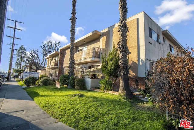 view of property exterior with a yard and a balcony