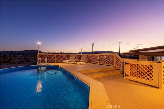 pool at dusk featuring a wooden deck