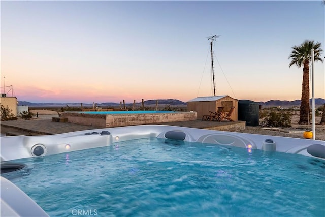 pool at dusk featuring a shed and a mountain view