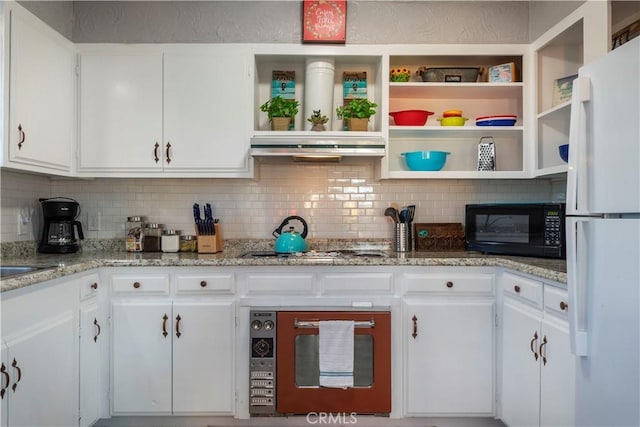 kitchen featuring white refrigerator, tasteful backsplash, light stone counters, and white cabinets