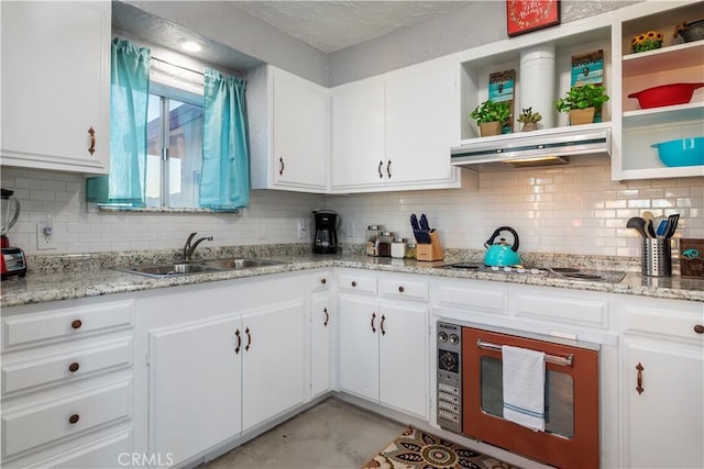 kitchen with sink, backsplash, light stone counters, gas stovetop, and white cabinets