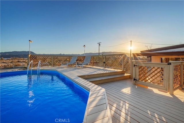 pool at dusk featuring a wooden deck