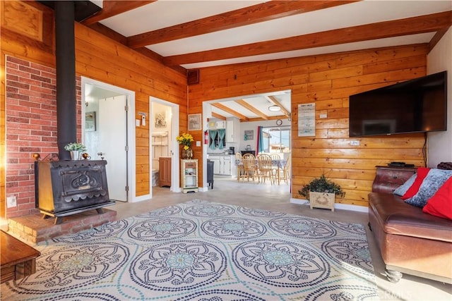 living room featuring wood walls, beam ceiling, and a wood stove