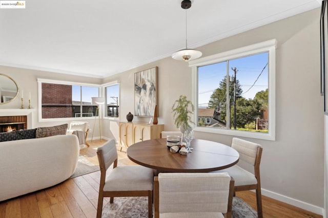 dining space with hardwood / wood-style flooring, a fireplace, and ornamental molding