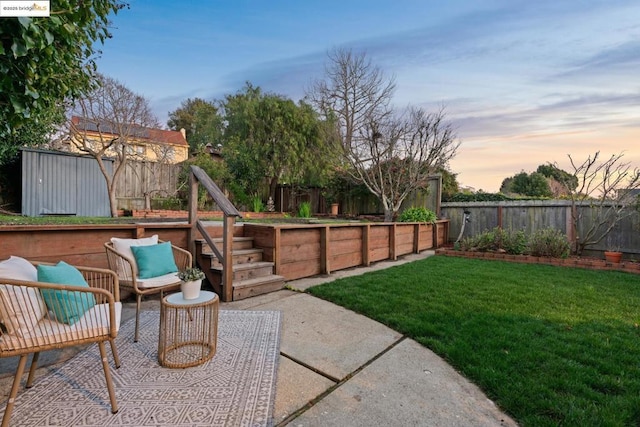 yard at dusk with an outdoor hangout area, a shed, and a patio