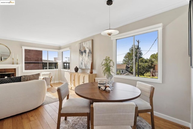 dining space featuring crown molding, wood-type flooring, and a brick fireplace