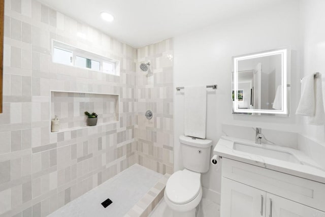 bathroom featuring vanity, toilet, and a tile shower