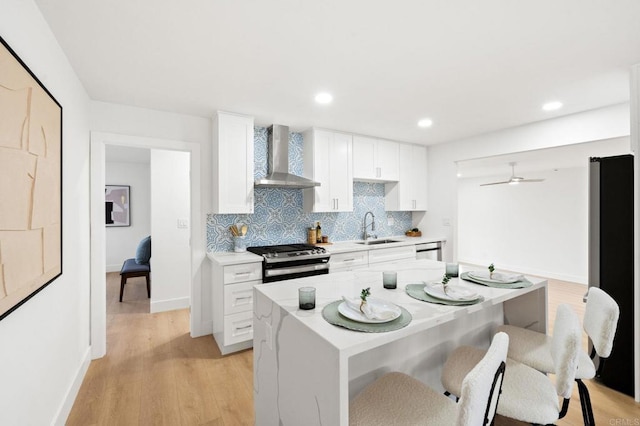 kitchen with sink, white cabinetry, tasteful backsplash, stainless steel appliances, and wall chimney range hood