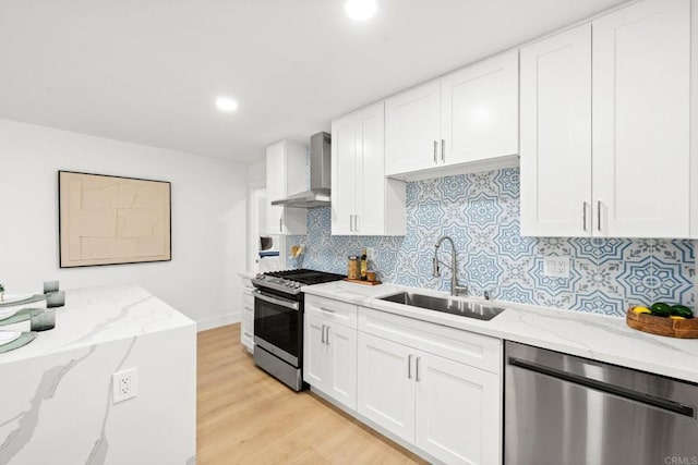 kitchen featuring sink, white cabinets, stainless steel appliances, light stone countertops, and wall chimney exhaust hood