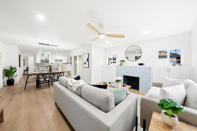 living room featuring ceiling fan, a fireplace, and light hardwood / wood-style floors