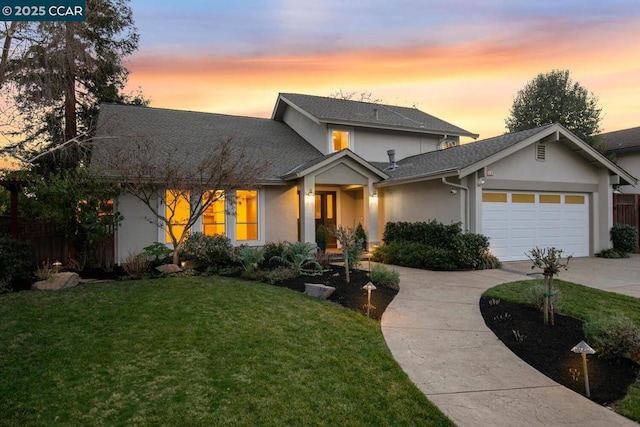 view of front of home with a garage and a lawn