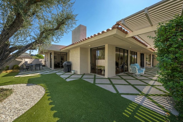 back of property featuring a yard, a pergola, and a patio